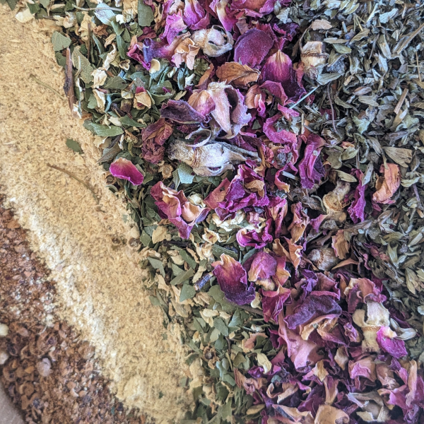 crushed hawthorn berries, crushed ginger, hawthorn leaves and flowers, rose petals and lemon balm herbs in a bowl